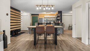 A modern kitchen with a central island, bar stools, and a hanging light fixture. - 9 Peaks | Scandinavian | Pool | Hot Tub | Beach (Invermere)