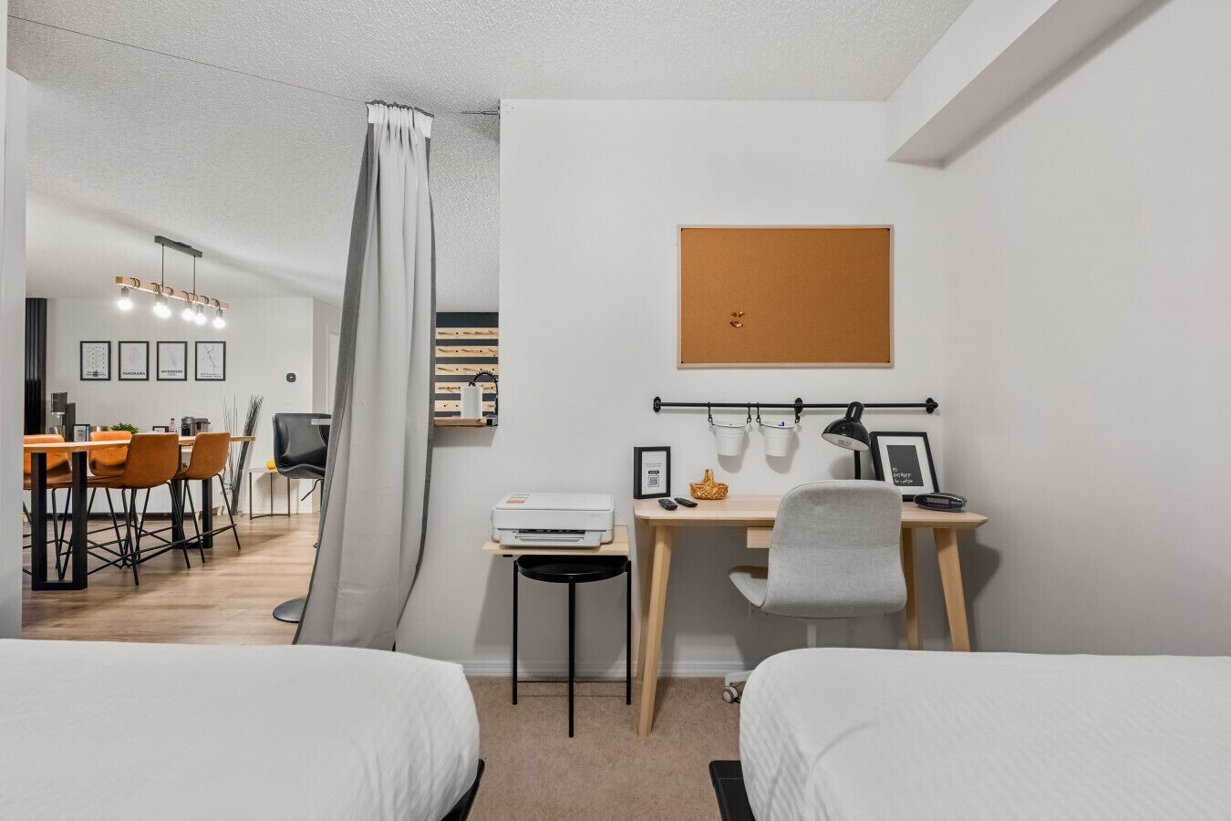 Une chambre d’hôtel moderne équipée d’un bureau, de deux lits, d’un coin repas et d’une douche.