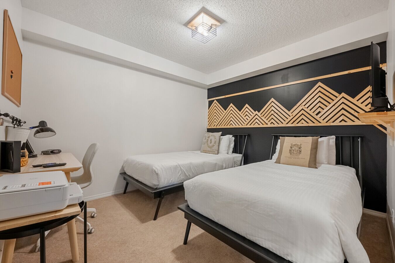 Et hotelværelse med to enkeltsenge, et skrivebord med en computer og en stol.