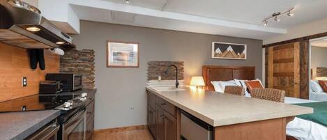 A modern kitchen with a central island, built-in appliances, and a rustic brick backsplash.