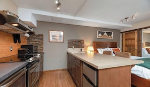 A modern kitchen with a central island, built-in appliances, and a rustic brick backsplash.