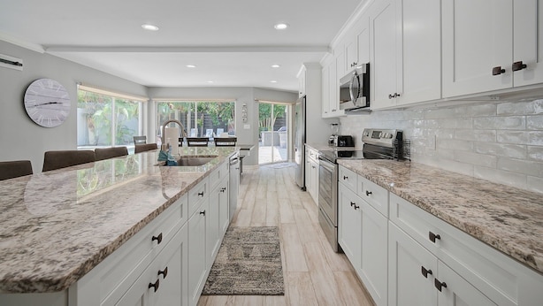 Una cocina moderna con armarios blancos, encimeras de granito y una isla grande.