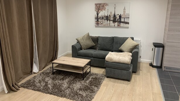 Un salon avec un canapé gris, une table basse en bois et un tapis à poils longs gris.