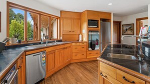 A modern kitchen with wooden cabinets, a stainless steel refrigerator, and a built-in oven.