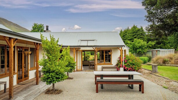 A rustic building with a covered patio, wooden beams, and a bench.