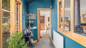 A narrow hallway with teal walls, wooden trim, and a view into a dining area.