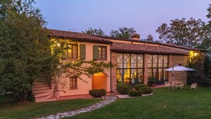 Une maison à deux étages, avec un toit en tuiles, de grandes fenêtres et une cheminée en pierre.