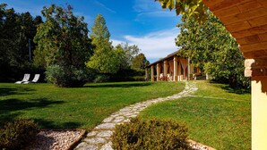 Un jardin avec un chemin de pierre menant à un bâtiment doté d’un patio couvert.