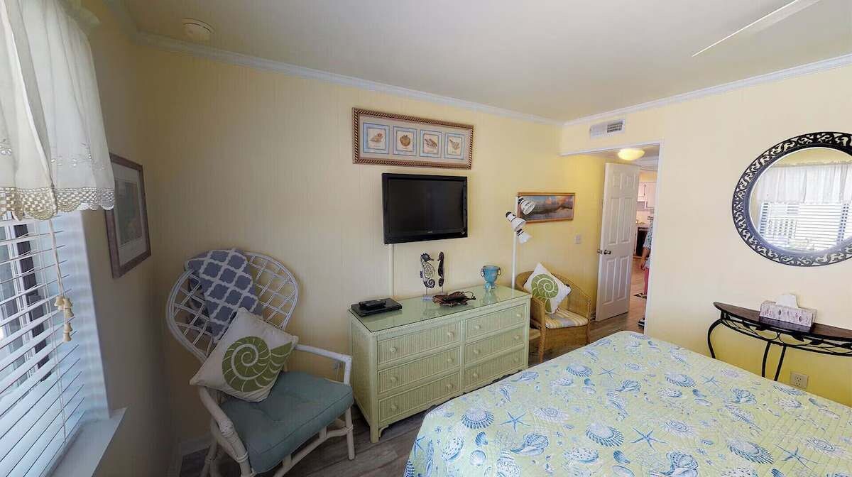Une chambre à coucher avec un lit, une commode, un téléviseur et une chaise.