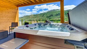 A hot tub under a wooden pergola with a scenic mountain view.