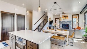 A modern kitchen with a central island, built-in ovens, and pendant lighting.