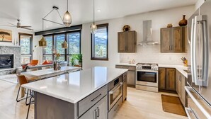 A modern kitchen with a large island, stainless steel appliances, and wooden cabinets.