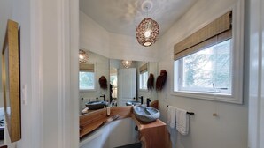 Ein modernes Badezimmer mit einem großen Spiegel, einem Steinsinkenschalen und einem Fenster mit Blick auf Bäume.