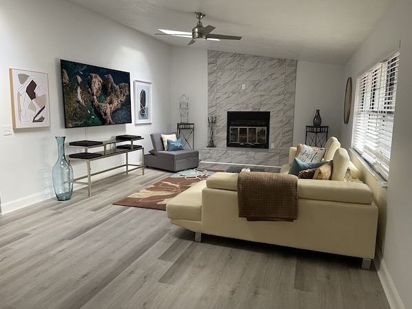 A modern living room with a sofa, a coffee table, a fireplace, and artwork on the walls.