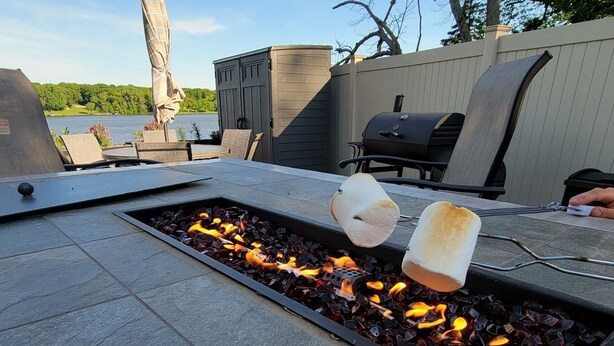 Ein Lagerfeuer, über den Flammen werden zwei Marshmallows geröstet.