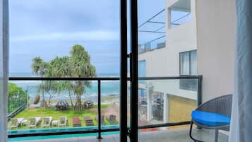 Relax on the spacious balcony with ocean views, lounge chairs, and a dining table.