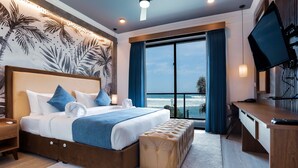Una habitación de hotel moderna con una cama grande, un escritorio y vistas al océano.