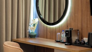 A modern desk with a round mirror, a chair, a small plant, and a refrigerator with beverages. - Beach & Bliss Mirissa (Mirissa)