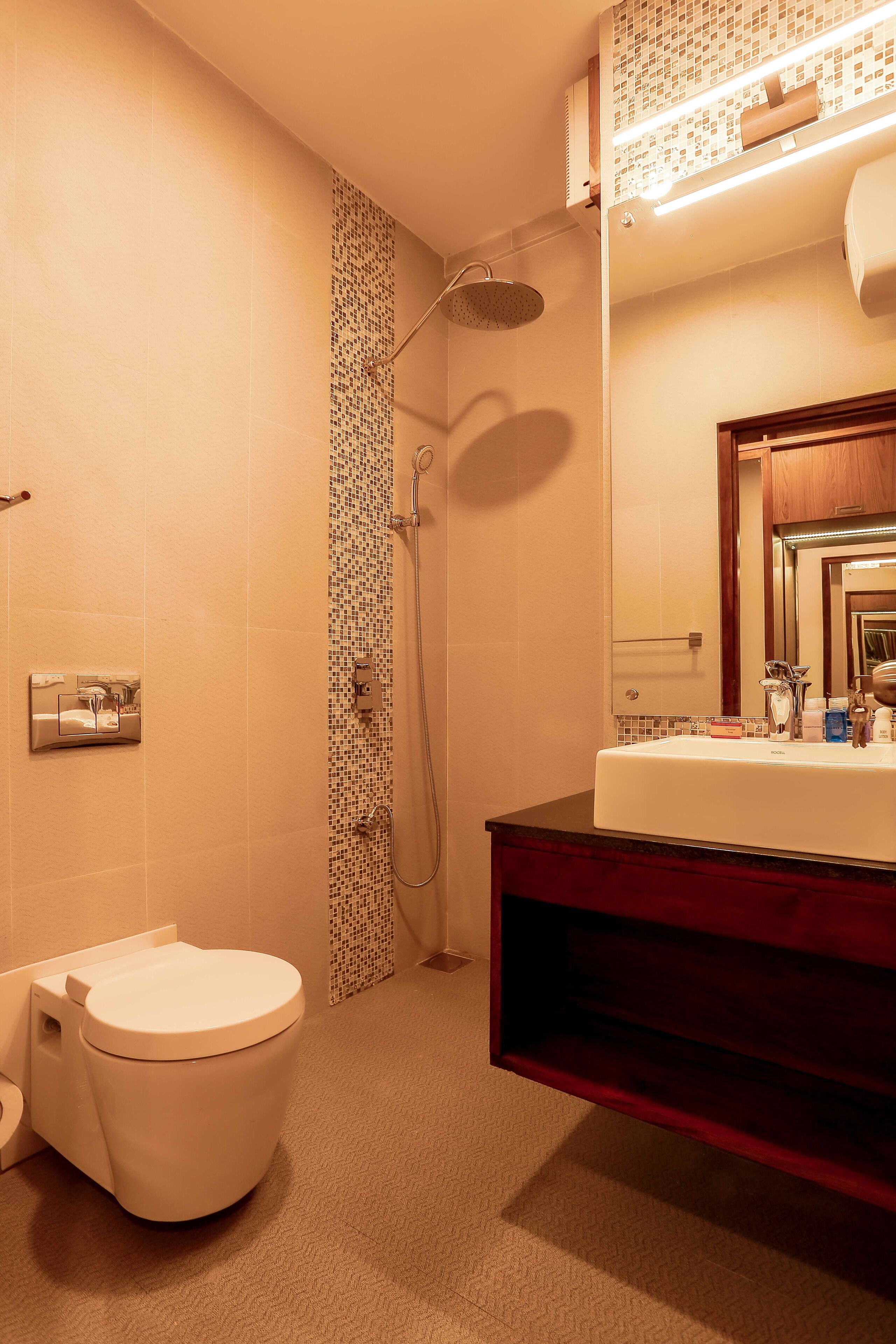 Ein Badezimmer mit Toilette, Dusche und Waschbecken mit Spiegel.