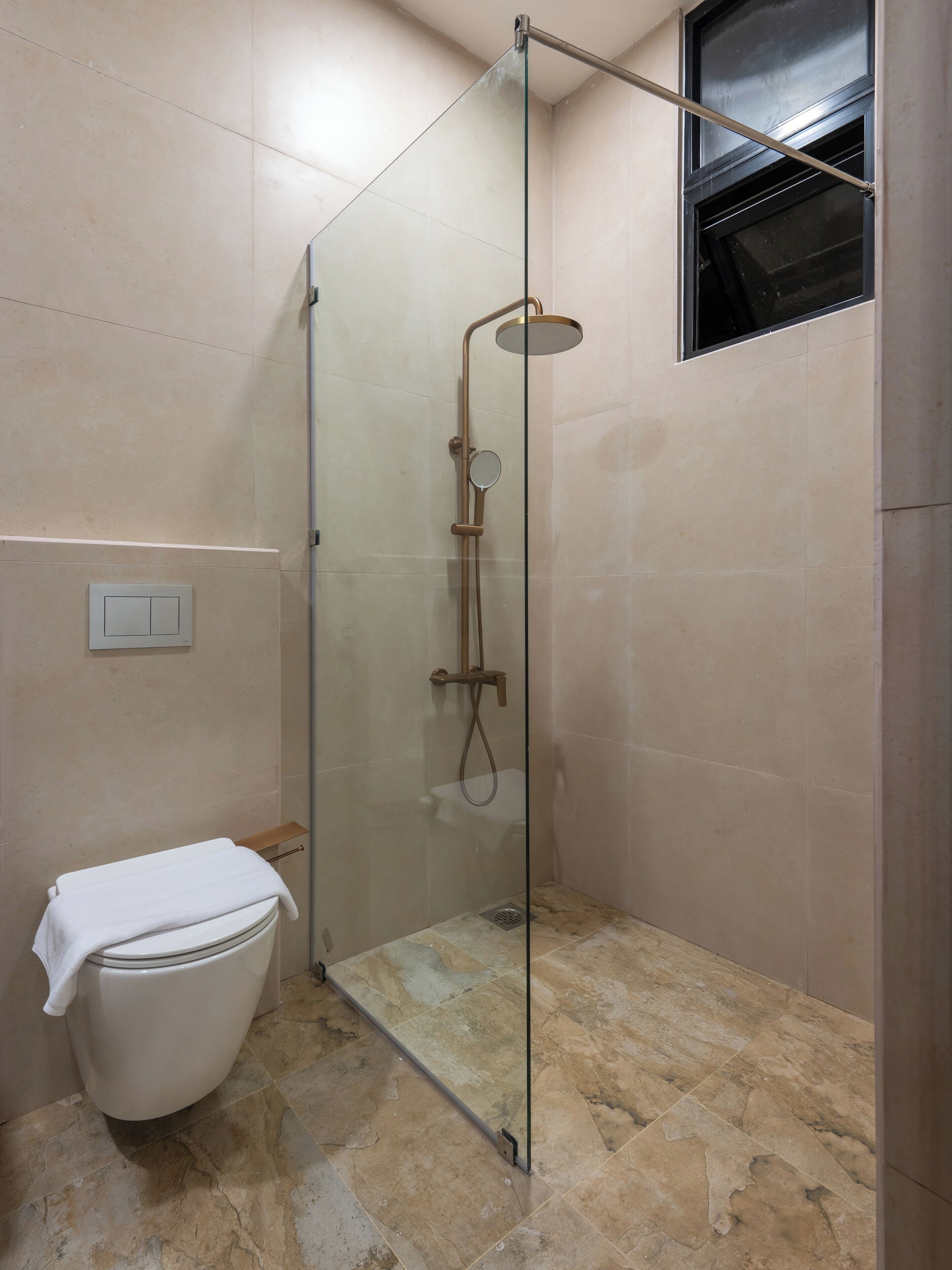 A bathroom with a glass-enclosed shower, a toilet, and a window.