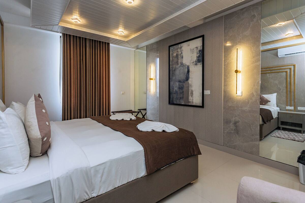 A modern hotel room with a large bed, a mirror, and a wall-mounted artwork.