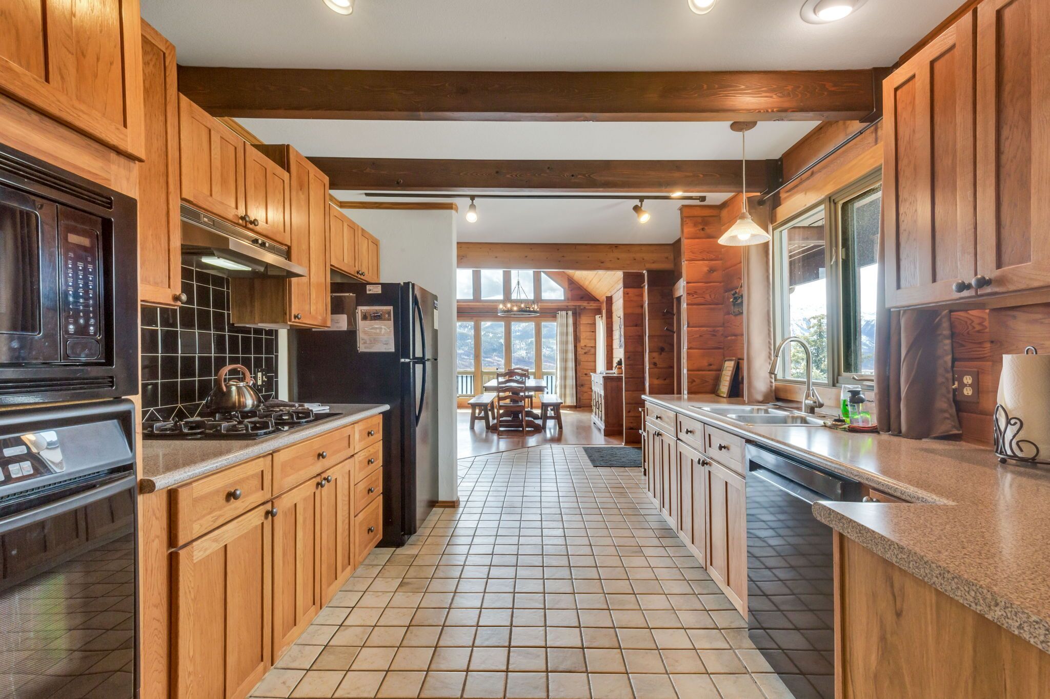 A spacious kitchen with wooden cabinets, a central island, and a view to a dining area.