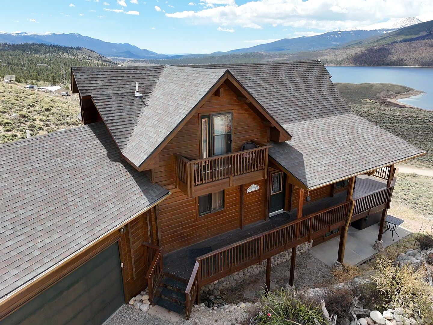 Eine zweistöckige Blockhütte mit Balkon, eingebettet in eine felsige Landschaft und einem See.
