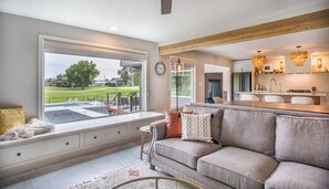 Una sala de estar moderna con un ventanal que da a una piscina y un campo de golf.