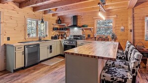 L’intérieur d’un chalet en bois comprend une cuisine, un coin repas et un banc dont l’assise est recouverte de peau de vache.