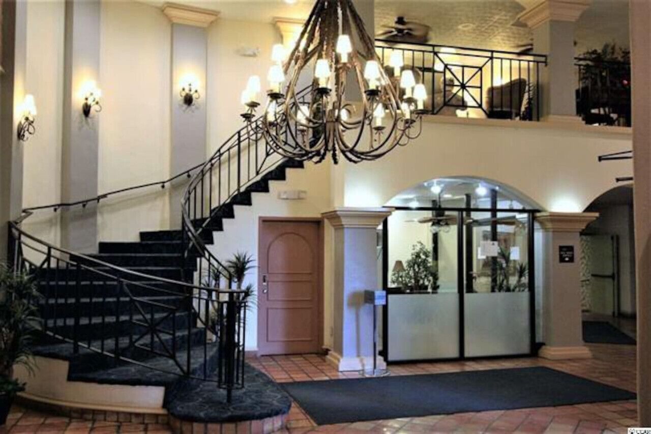 Un vaste hall d’entrée avec un escalier, un lustre et un comptoir d’accueil.