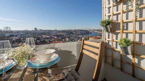 Een balkon met een eettafel, met uitzicht op een stadsgezicht met gebouwen en een waterpartij.