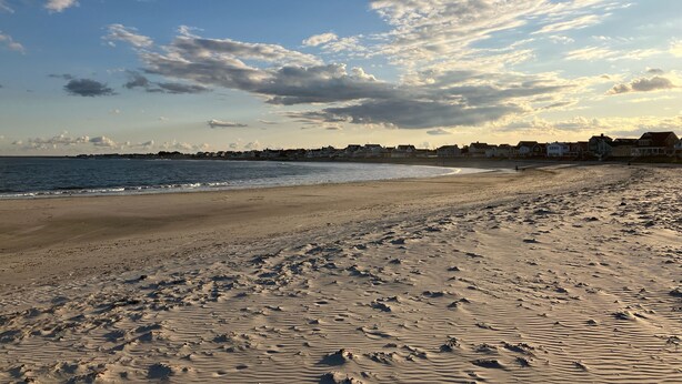 A beach with a clear sky and scattered clouds.