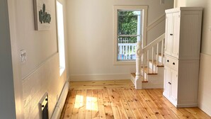 A spacious room with wooden flooring, a staircase, and a white cabinet.