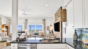 A modern kitchen with white cabinets, a black countertop, and a view of the beach. - Gulf-Front Duplex | Pet Friendly | Pools and Pier Access (Gulf Shores)