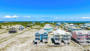 A coastal residential area with beachfront properties featuring multiple stories, balconies, and wooden walkways leading to the beach. - Gulf-Front Duplex | Pet Friendly | Pools and Pier Access (Gulf Shores)