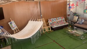 Una cadira de corda, un sofà i una cadira en una habitació amb parets de fusta i un sòl verd.