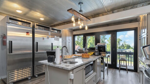Una cocina moderna con electrodomésticos de acero inoxidable, encimera de granito y vistas amplias por puertas correderas de vidrio.