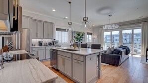 A modern kitchen with a central island, stainless steel appliances, and pendant lighting.