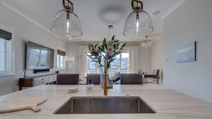 A modern kitchen with a large island, pendant lighting, and a view of the city.