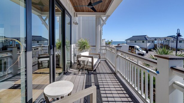 A wooden deck with a ceiling fan, a table, and a chair.