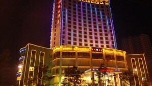 A multi-story hotel with a prominent curved facade and illuminated signage. - Shengjing Hotel (Fuyuan)