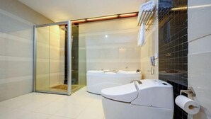 A modern bathroom with a glass shower enclosure, a double toilet, and a large bathtub. - Shengjing Hotel (Fuyuan)