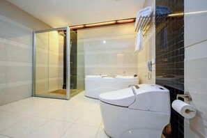 A modern bathroom with a glass shower enclosure, a double toilet, and a large bathtub. - Shengjing Hotel (Fuyuan)