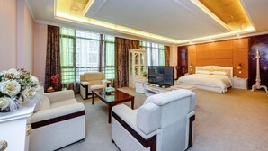A hotel room with a large bed, a TV, a sofa, and a desk. - Shengjing Hotel (Fuyuan)