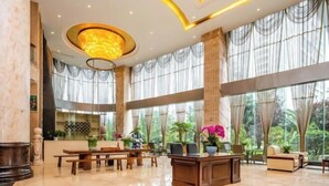 A spacious lobby with a large desk, seating area, and large windows with sheer curtains. - Shengjing Hotel (Fuyuan)
