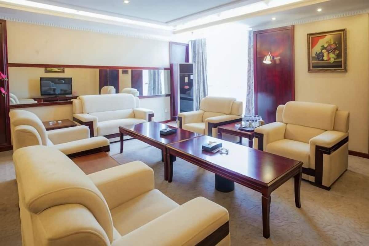 A hotel living room with a sofa set, a coffee table, a TV, and a painting on the wall.