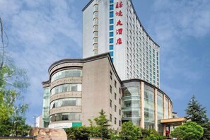 A modern hotel with a curved facade, multiple floors, and large windows. - Shengjing Hotel (Fuyuan)