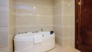 A modern bathroom with a freestanding bathtub, a wooden door, and tiled walls. - Shengjing Hotel (Fuyuan)