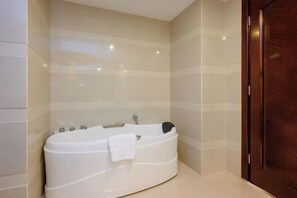 A modern bathroom with a freestanding bathtub, a wooden door, and tiled walls. - Shengjing Hotel (Fuyuan)