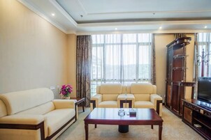 Una sala de estar con un sofá, sillones, una mesa de centro, un televisor y un mueble de almacenamiento.